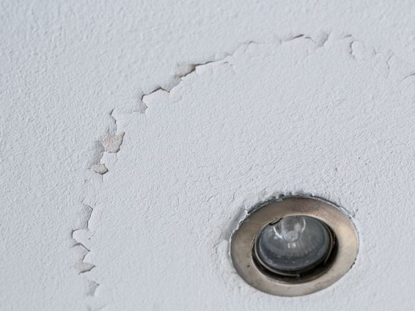 Peeling paint on a ceiling around a light