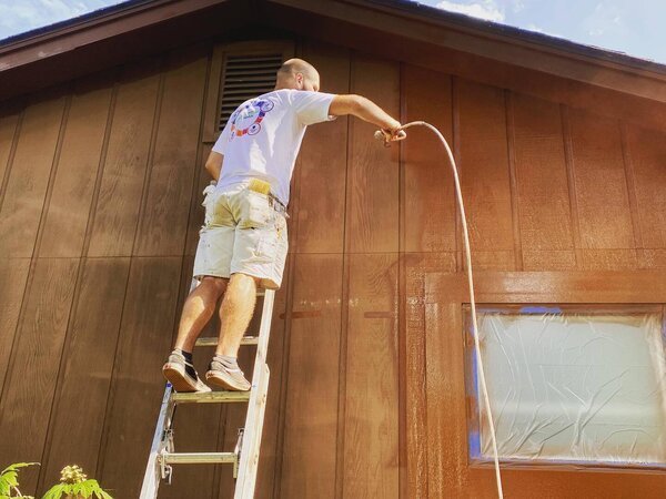 Painting a home exterior while on a ladder