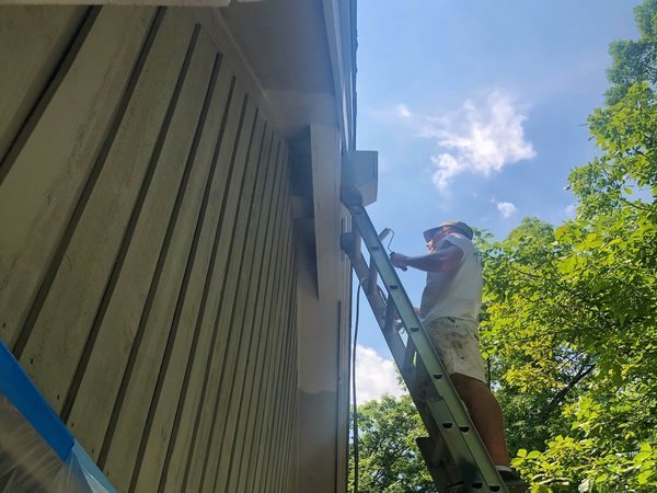 Staining a wood exterior on a ladder