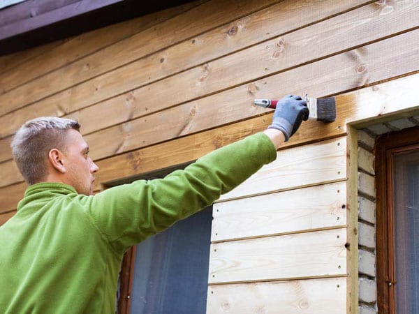Using a brush instead of a sprayer to paint a homes wood exterior