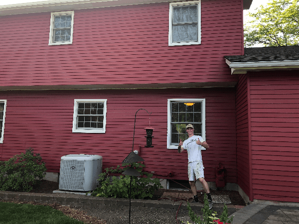 Tribble team member posing with house after painting it red