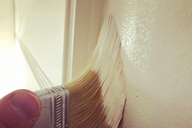 A close up of a Tribble Painting employee applying paint to trim