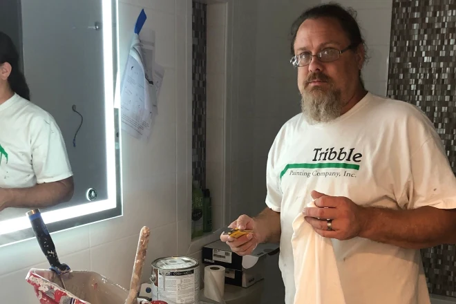 A professional painter works on painting a bathroom
