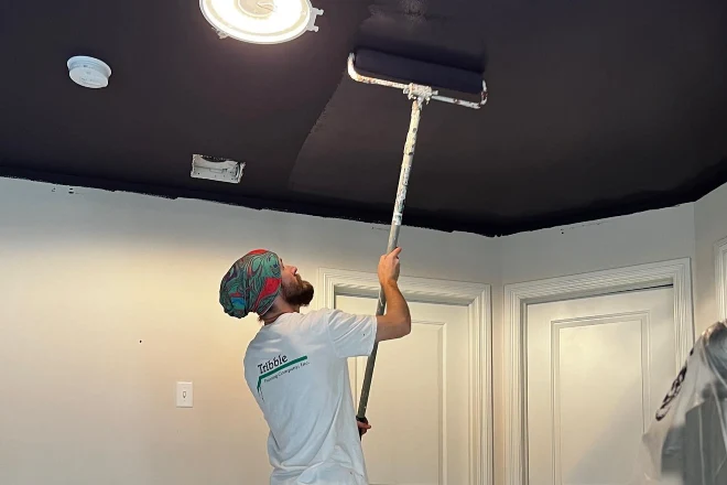 A-Tribble-painter-applies-black-paint-to-a-ceiling