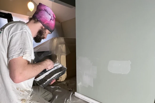 A-Tribble-painter-applies-gray-paint-to-a-wall