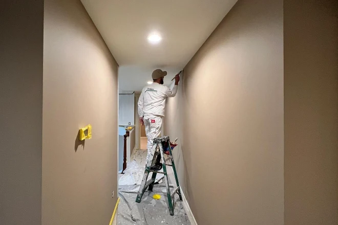 A-Tribble-painter-applying-a-neutral-color-to-a-hallway