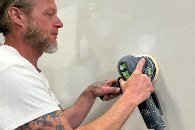A Tribble Painting Company professional sands a wall in preparation for painting