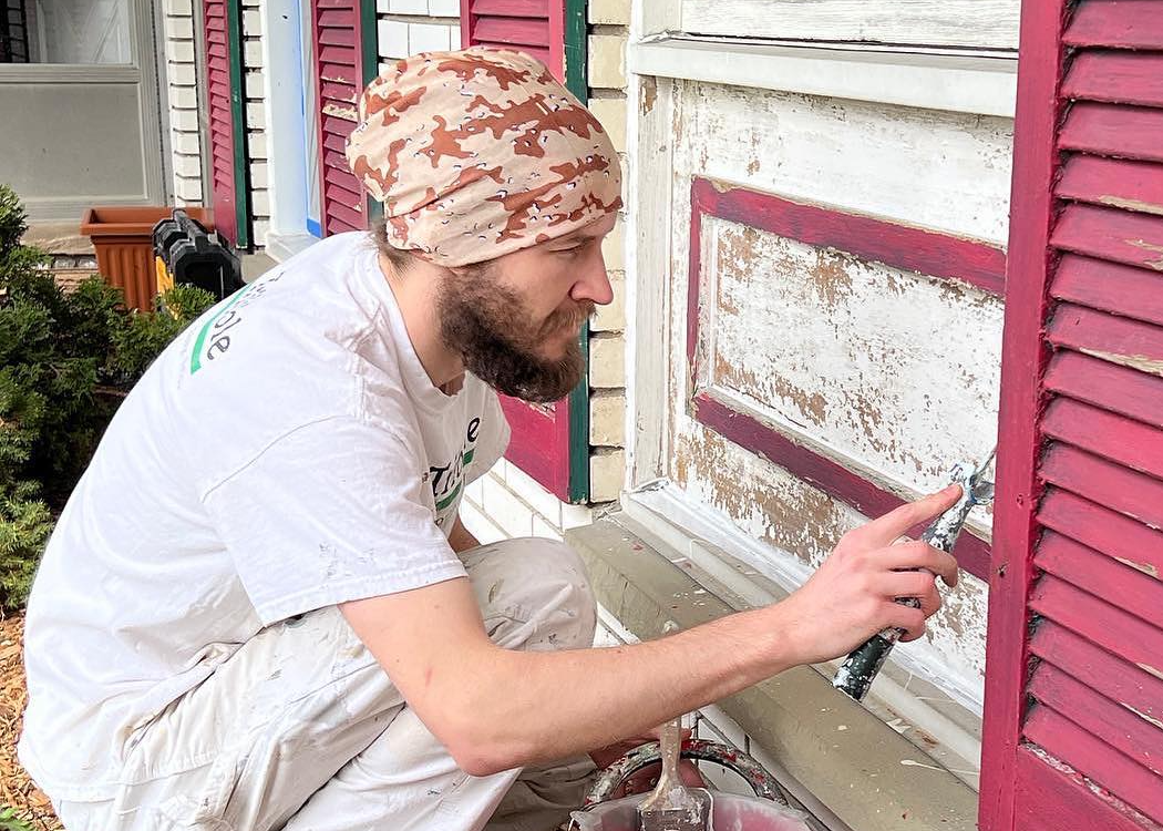A Tribble Painting employee carefullt removes old paint from a home's exterior.