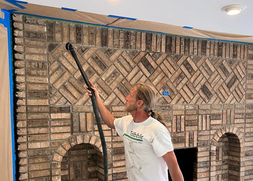 A Tribble Painting employee carefully vacuums a masonry surface