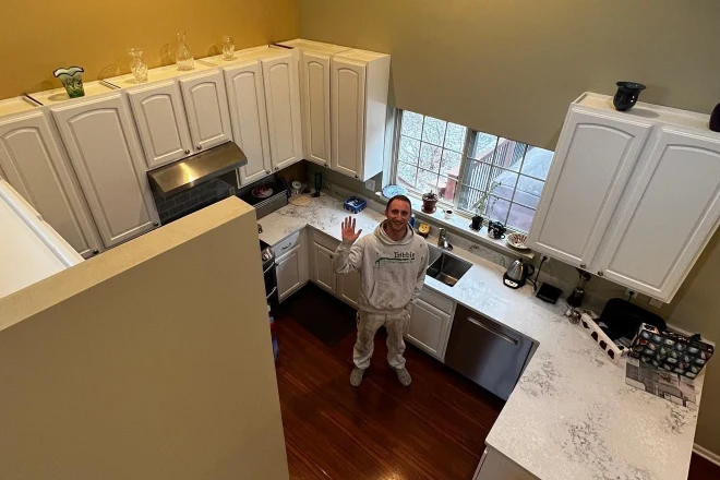 A Tribble Painting employee stands in a kitchen with freshly painted cabinets