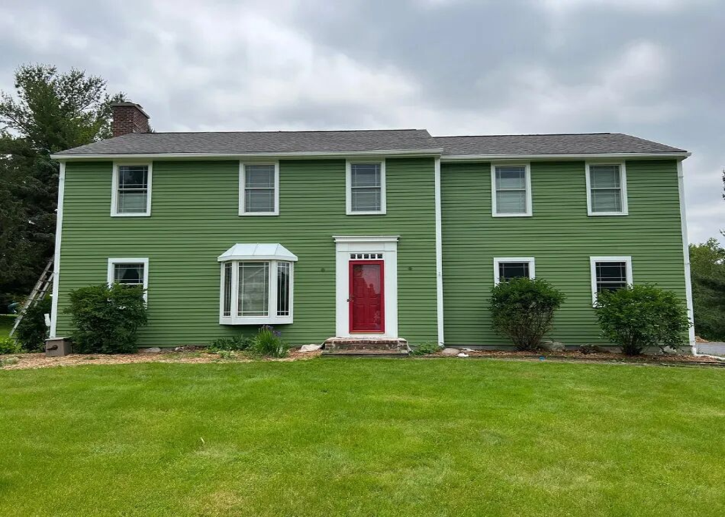 A two-story residential home with a green exterior paint job