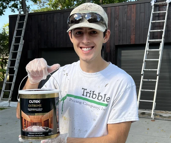 Tribble team member with a can of paint in front of a house project