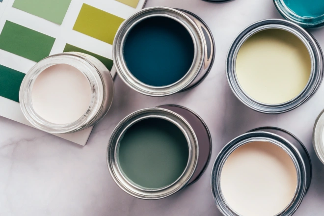 Paint cans with different green and beige colors, color charts on background