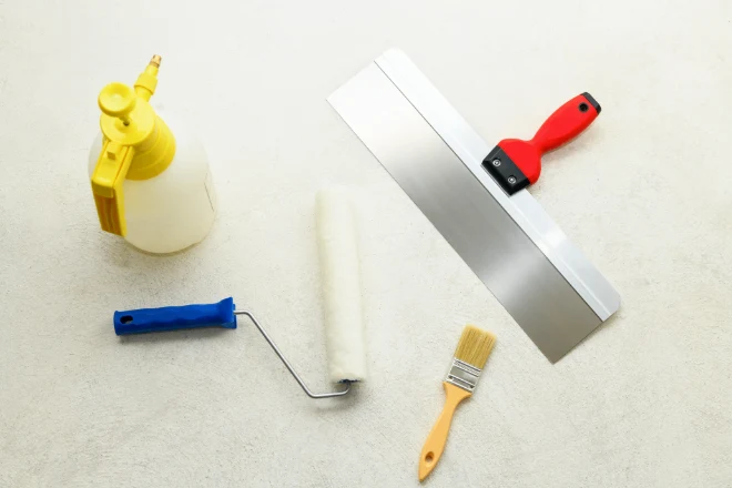 Paint set: roller, brush, spatula and liquid sprayer on the concrete floor, close-up. 