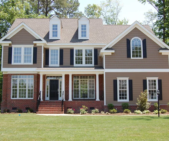 Large 3 story home painted light brown with brick
