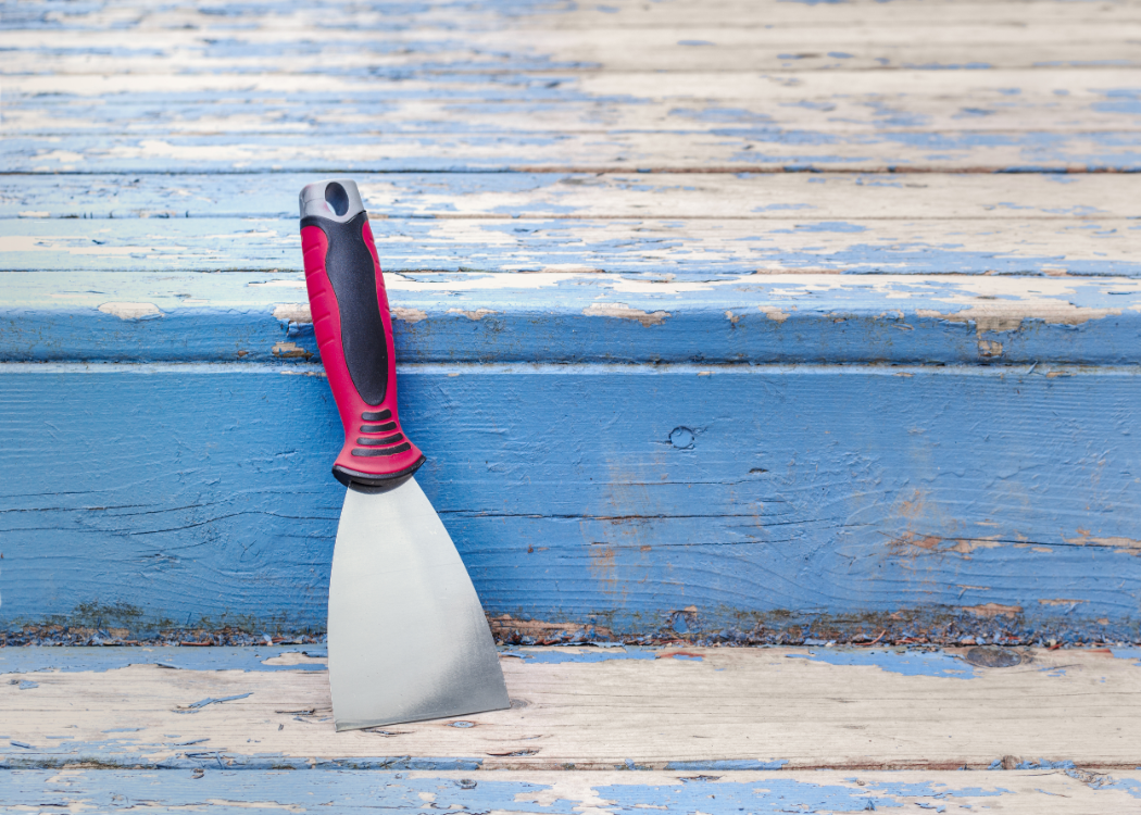 Putty knife used as a paint scraper on weathered boards