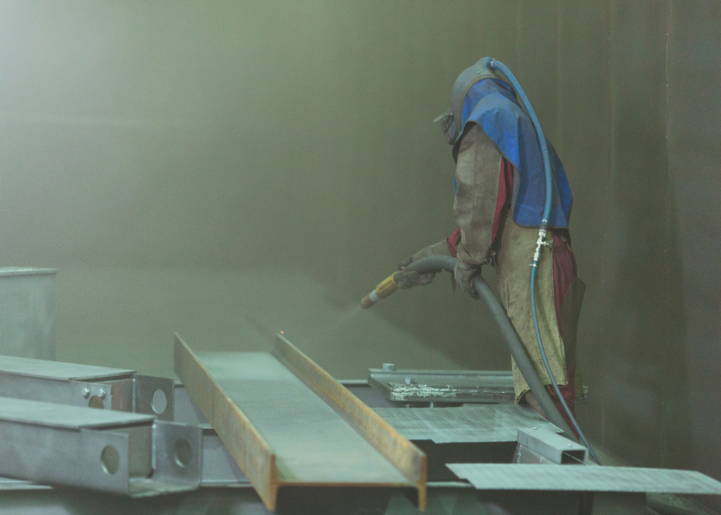 Person sandblasting metal.