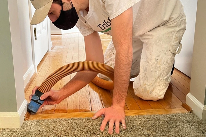 Tribble Painting Company employee carefully vacuums around the baseboard in a home
